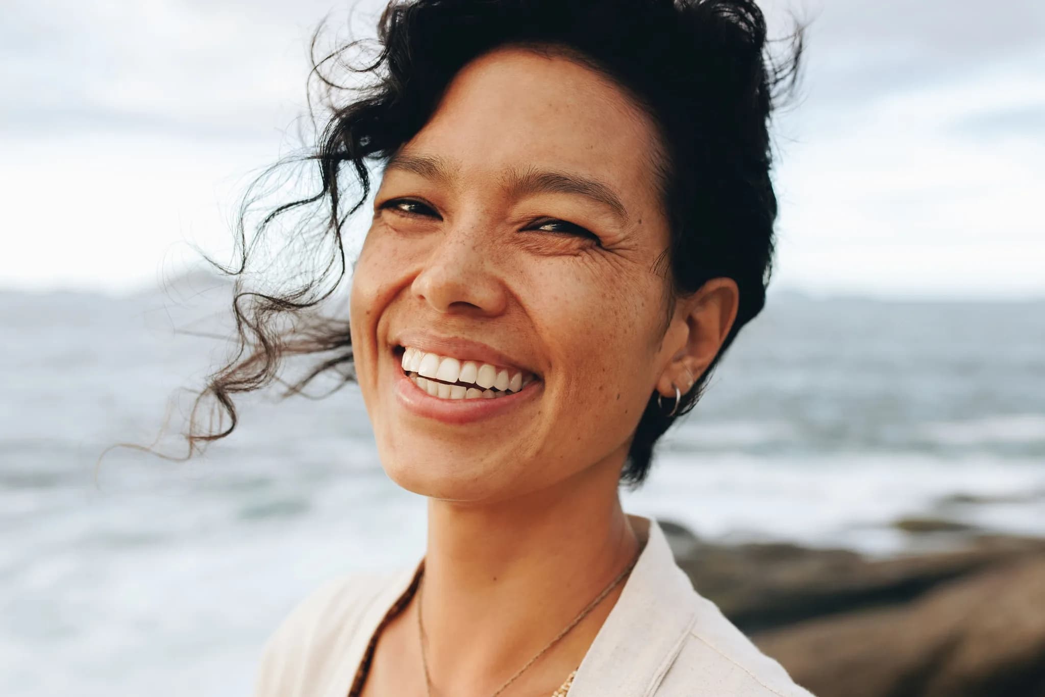 Smiling woman by the sea, hair in the wind
